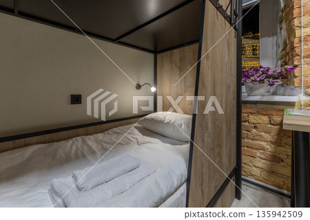 Close-up of a wooden bunk bed in a loft hostel with night window 135942509