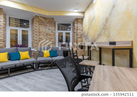 Modern hostel common area with lounge seating and coworking zone Modern hostel common area with lounge seating and coworking zone 135942511