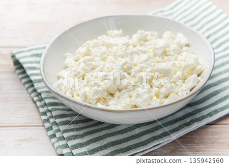 Cottage cheese in bowl on wooden table with green napkin Cottage cheese in bowl on wooden table with green napkin 135942560