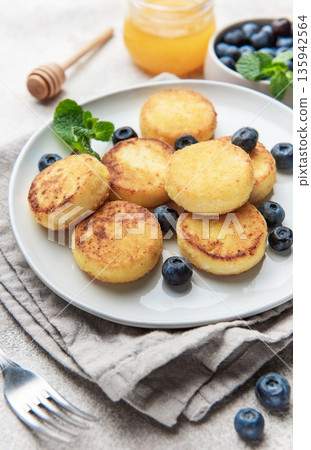 Syrniki cottage cheese pancakes with blueberries and honey for breakfast Syrniki cottage cheese pancakes with blueberries and honey for breakfast 135942564