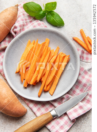 Raw sweet potato sticks on plate with basil 135942572