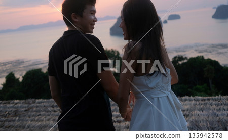 Romantic Couple Holding Hands at Sunset Over Tropical Sea In Summer Season 135942578