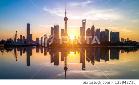 Urban cityscape panorama featuring a vibrant sunset and sunrise reflection over the river and lake water with a downtown building skyline and skyscraper view Urban cityscape panorama featuring a vibrant sunset and sunrise reflection over the river and lake water with a downtown building skyline and skyscraper view 135942733