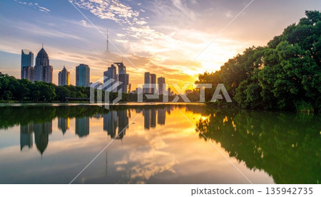 Urban cityscape panorama featuring a vibrant sunset and sunrise reflection over the river and lake water with a downtown building skyline and skyscraper view Urban cityscape panorama featuring a vibrant sunset and sunrise reflection over the river and lake water with a downtown building skyline and skyscraper view 135942735