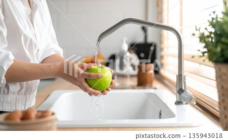 A woman practices good hygiene by washing her hands with soap and water at the bathroom sink faucet to stay clean and healthy at home A woman practices good hygiene by washing her hands with soap and water at the bathroom sink faucet to stay clean and healthy at home 135943018