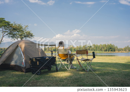 asian couple fun happy and relax with camping and picnic at side of lake with mountain background asian couple fun happy and relax with camping and picnic at side of lake with mountain background 135943623
