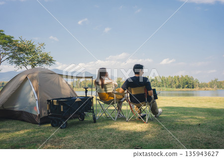 asian couple fun happy and relax with camping and picnic at side of lake with mountain background asian couple fun happy and relax with camping and picnic at side of lake with mountain background 135943627