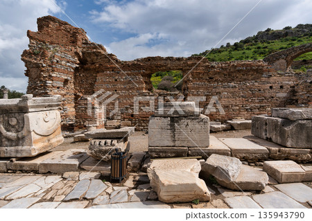 Ancient ruins of Ephesus featuring carved stone blocks and weathered brick walls under a cloudy sky, Ephesus Turkey 135943790