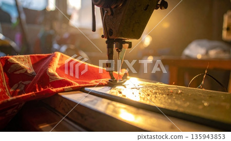 A macro shot of a metal needle and thread on an industrial sewing machine stitching fabric in a textile factory to craft fashion clothing A macro shot of a metal needle and thread on an industrial sewing machine stitching fabric in a textile factory to craft fashion clothing 135943853