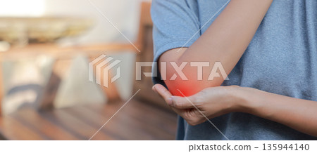 Close-up of woman hand holding painful injured elbow with red inflamed spot. Concept of joint bone pain, muscle injury, arthritis, tendonitis, or ache from sports or work in outdoor background. Close-up of woman hand holding painful injured elbow with red inflamed spot. Concept of joint bone pain, muscle injury, arthritis, tendonitis, or ache from sports or work in outdoor background. 135944140