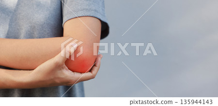 Close-up of woman hand holding painful injured elbow with red inflamed spot. Concept of joint bone pain, muscle injury, arthritis, tendonitis, or ache from sports or work in outdoor background. Close-up of woman hand holding painful injured elbow with red inflamed spot. Concept of joint bone pain, muscle injury, arthritis, tendonitis, or ache from sports or work in outdoor background. 135944143