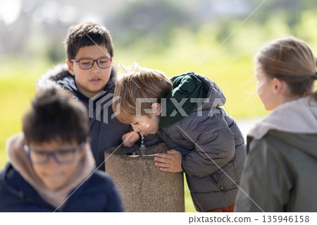 Children drinking water from fountain in park 135946158