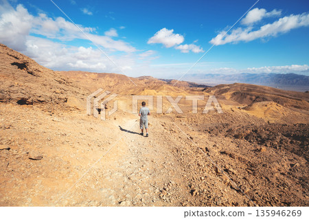 The young man is hiking in the desert on a sunny day. Eilat mountains in the Negev desert, Israel The young man is hiking in the desert on a sunny day. Eilat mountains in the Negev desert, Israel 135946269