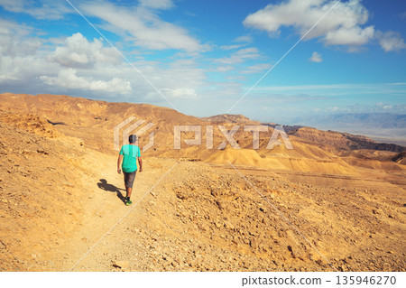 The young man is hiking in the mountain desert. Eilat mountains in the Negev desert, Israel The young man is hiking in the mountain desert. Eilat mountains in the Negev desert, Israel 135946270