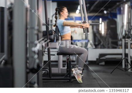Woman exercising chest press machine in modern gym Woman exercising chest press machine in modern gym 135946317