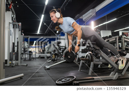 Woman exercising on hyperextension bench building core strength Woman exercising on hyperextension bench building core strength 135946329