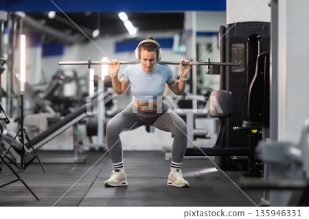 Woman exercising with barbell squats in a modern gym 135946331