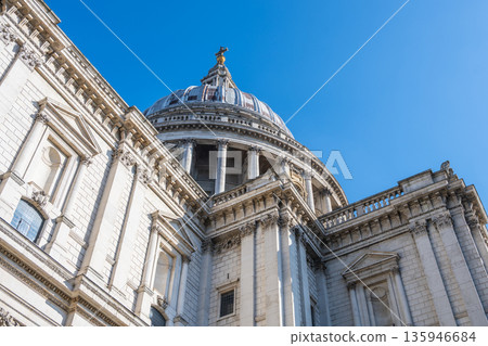 Visitors look up at the dome of St Pauls Cathedral in London. The structure features detailed architecture and stands tall against a bright blue sky. It is an iconic part of the city. Visitors look up at the dome of St Pauls Cathedral in London. The structure features detailed architecture and stands tall against a bright blue sky. It is an iconic part of the city. 135946684