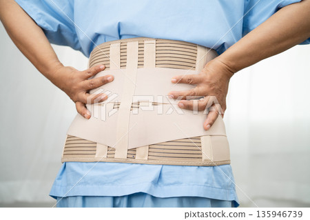 Asian lady patient wearing back pain support belt for orthopedic lumbar with walker. 135946739