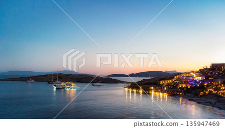 Night view to large illuminated boat near luxury resort, colorful lights reflect on the surface of the water sea. Outdoor resort in europe tourist islands. View harbor at night Night view to large illuminated boat near luxury resort, colorful lights reflect on the surface of the water sea. Outdoor resort in europe tourist islands. View harbor at night 135947469
