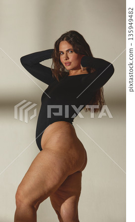Curvy woman embracing body confidence in black bodysuit in studio Curvy woman embracing body confidence in black bodysuit in studio 135949482