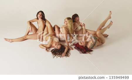 Group of diverse women relaxing together in lingerie on studio background. 135949499