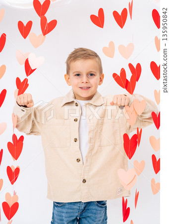 Confident smiling child showing positive gesture surrounded by red hearts. Love, strength, positive emotions and Valentines Day concept Confident smiling child showing positive gesture surrounded by red hearts. Love, strength, positive emotions and Valentines Day concept 135950842