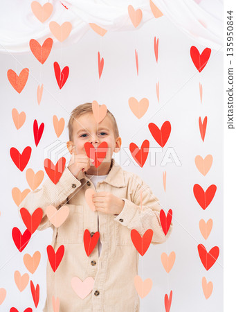 Cute child kissing heart shape decoration on white background. Love, tenderness, affection and Valentines Day concept 135950844