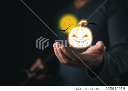 A person holds glowing Halloween-themed icons including a carved pumpkin, bats, and full moon, symbolizing spooky celebration, autumn festivity, and traditional Halloween night atmosphere. A person holds glowing Halloween-themed icons including a carved pumpkin, bats, and full moon, symbolizing spooky celebration, autumn festivity, and traditional Halloween night atmosphere. 135950959