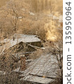 Snow-covered houses in countryside village on frosty morning, smoke peacefully rises from chimneys. 135950964