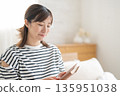 A woman reading in a bedroom 135951038