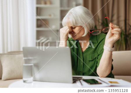 Elderly woman feeling eye strain or fatigue while using laptop at home Elderly woman feeling eye strain or fatigue while using laptop at home 135951128