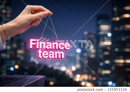 Female hand holding glowing pink finance team sign over night city 135951526