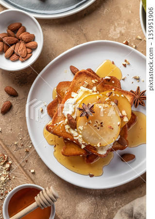 Yummy sweet toasts with caramelized pear, cream cheese, chopped nuts and honey syrup close up on brown textured background, top view Yummy sweet toasts with caramelized pear, cream cheese, chopped nuts and honey syrup close up on brown textured background, top view 135951906