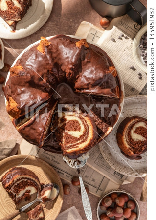 Chocolate marble bundt cake or zebra cake with chocolate glaze sliced on brown table background top view 135951932