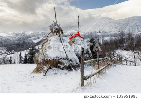 Traditional haystacks in snowy mountain village, Carpathian Mountains, Romania 135951983