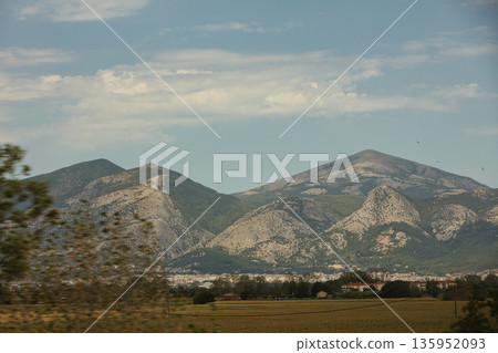 A sweeping mountain landscape in August 2025, with tiered, wooded hills under a clear summer sky. A sweeping mountain landscape in August 2025, with tiered, wooded hills under a clear summer sky. 135952093