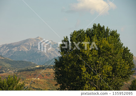 A sweeping mountain landscape in August 2025, with tiered, wooded hills under a clear summer sky. 135952095