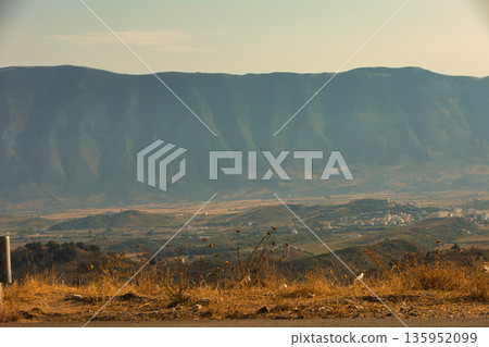 A sweeping mountain landscape in August 2025, with tiered, wooded hills under a clear summer sky. A sweeping mountain landscape in August 2025, with tiered, wooded hills under a clear summer sky. 135952099