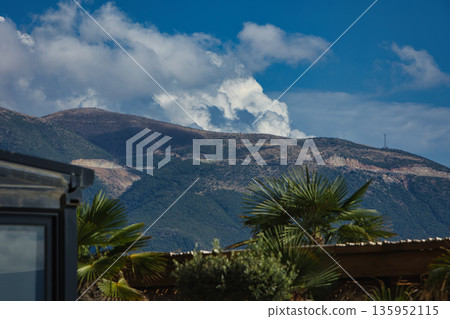 A sweeping mountain landscape in August 2025, with tiered, wooded hills under a clear summer sky. 135952115