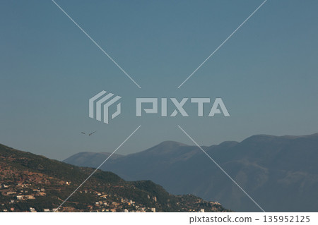 A sweeping mountain landscape in August 2025, with tiered, wooded hills under a clear summer sky. A sweeping mountain landscape in August 2025, with tiered, wooded hills under a clear summer sky. 135952125