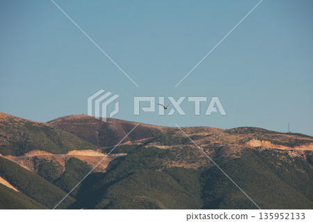 A sweeping mountain landscape in August 2025, with tiered, wooded hills under a clear summer sky. A sweeping mountain landscape in August 2025, with tiered, wooded hills under a clear summer sky. 135952133
