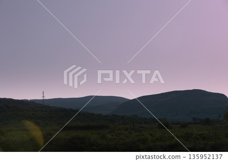 A sweeping mountain landscape in August 2025, with tiered, wooded hills under a clear summer sky. A sweeping mountain landscape in August 2025, with tiered, wooded hills under a clear summer sky. 135952137