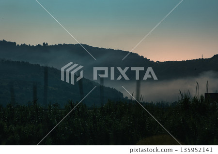 A sweeping mountain landscape in August 2025, with tiered, wooded hills under a clear summer sky. A sweeping mountain landscape in August 2025, with tiered, wooded hills under a clear summer sky. 135952141