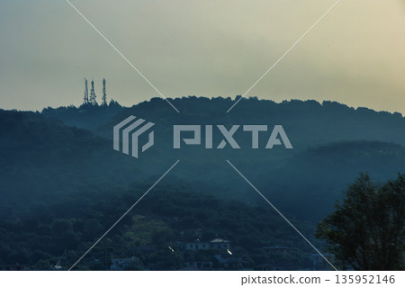 A sweeping mountain landscape in August 2025, with tiered, wooded hills under a clear summer sky. A sweeping mountain landscape in August 2025, with tiered, wooded hills under a clear summer sky. 135952146