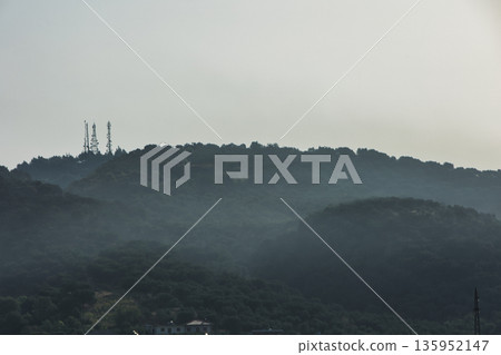 A sweeping mountain landscape in August 2025, with tiered, wooded hills under a clear summer sky. 135952147