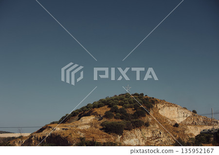 A sweeping mountain landscape in August 2025, with tiered, wooded hills under a clear summer sky. A sweeping mountain landscape in August 2025, with tiered, wooded hills under a clear summer sky. 135952167