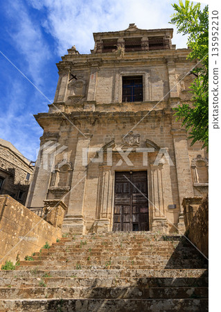 The Enna Cathedral at sunset with people sitting in front of it on stairs 135952210