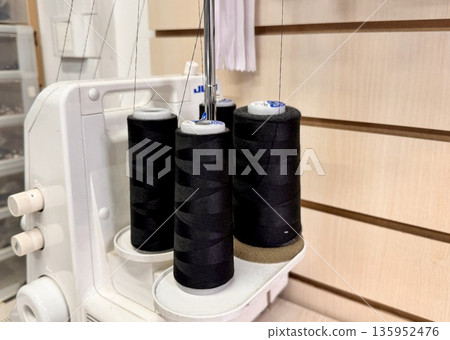 sewing workshop with a work area sewing machine filled with threads and working tools 135952476