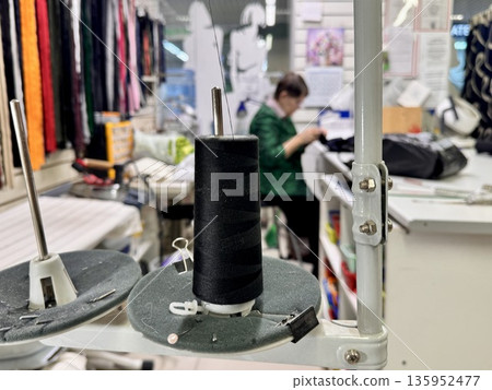 sewing workshop with a work area sewing machine filled with threads and working tools 135952477